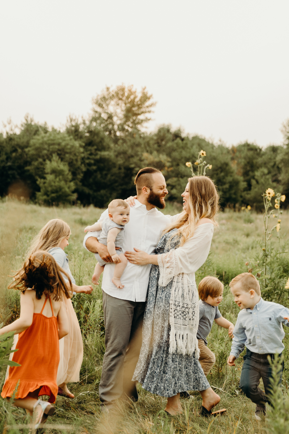 4 kids running around their parents in a field