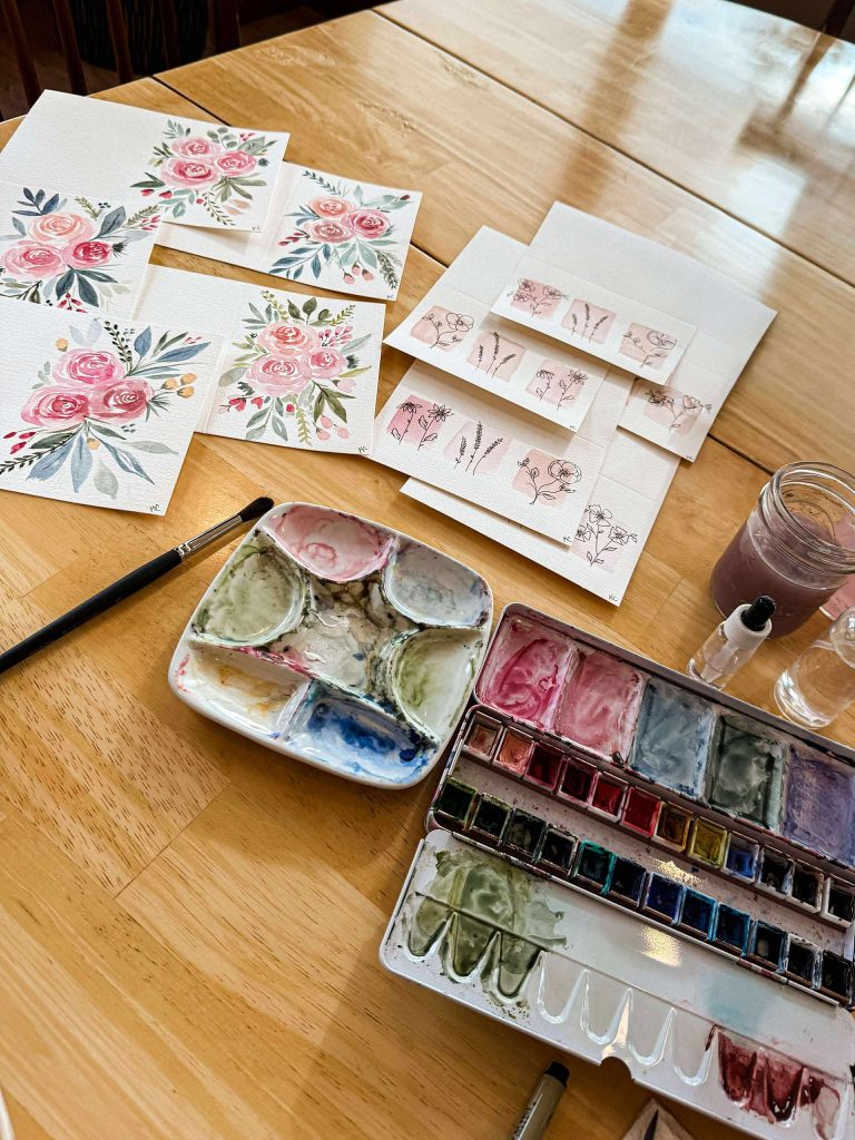 A table with watercolor paints and paintings