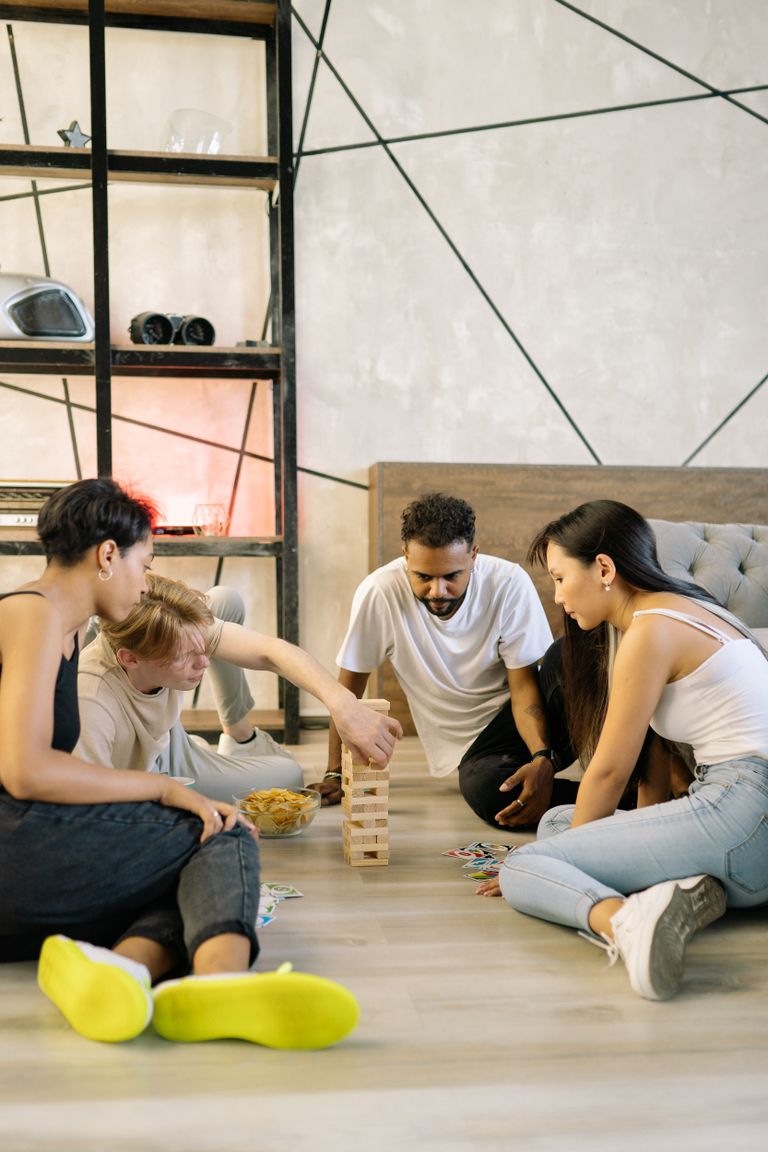 A diverse group of friends playing board games and cards indoors, enjoying leisure time.